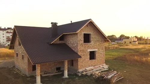 Aerial view of unfinished house with wooden roof structure covered with metal tile sheets under