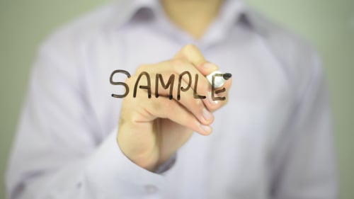 Hand Writes the Word Sample on Glass