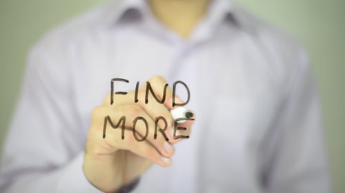 Hand Writes "Find More" on a Clear Surface