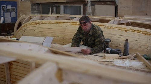 Carpinteiro estuda o rascunho do barco no estaleiro
