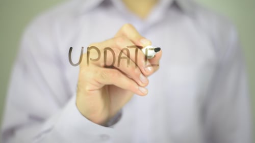 Hand Writes 'Update' on a Clear Surface