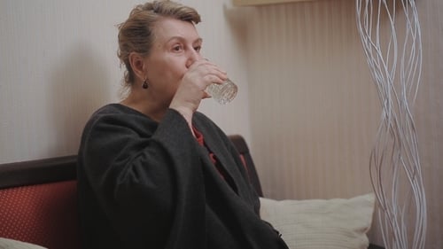 Woman Taking Pill with Water Inside Her Home