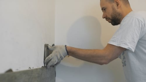 Man Installing Gray Tile on White Wall
