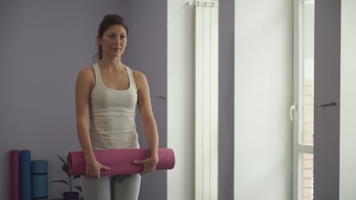 Woman Unrolls Yoga Mat in Bright Room