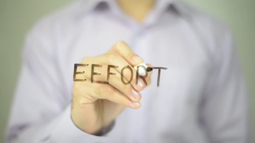 Hand Writes the Word Effort on Glass