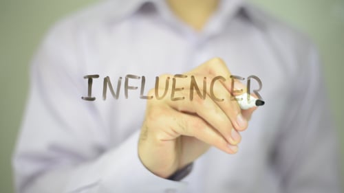 Man Writes the Word Influencer on Transparent Surface