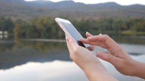 Woman Using Smartphone in Nature by Lake