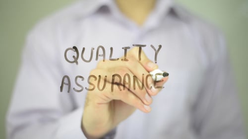 Hand Writes Quality Assurance With Marker Close Up