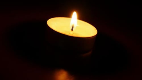 Small Candle Flame Flickering in the Darkness