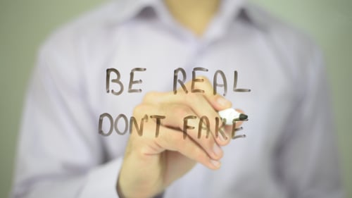 Hand Writes "Be Real, Don't Fake" on Clear Surface