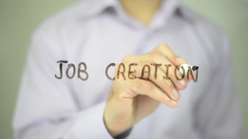 Hand Writes 'Job Creation' on Clear Surface