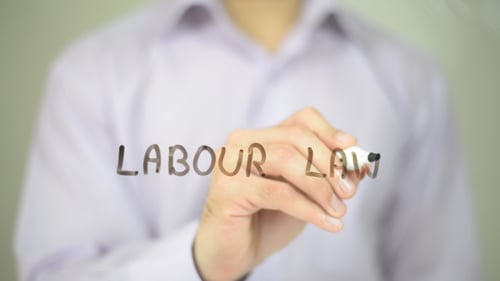 Hand Writes Labour Law on Clear Surface