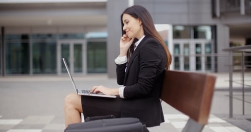 Stylish Woman Working Outdoors on Laptop and Smartphone