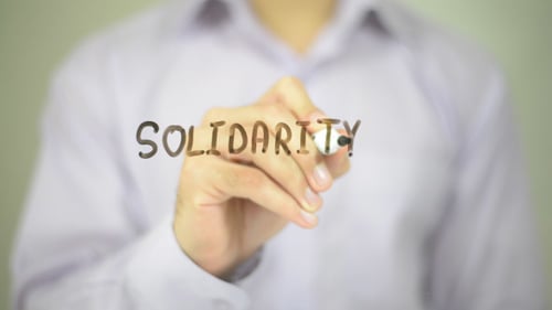 Hand Writing Solidarity on Glass Whiteboard