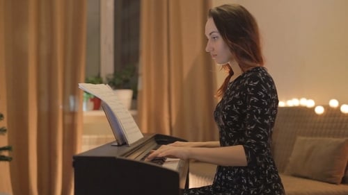 Woman Playing Piano in Cozy Lit Home