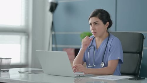 Indian Female Doctor Coughing while using Laptop in Office
