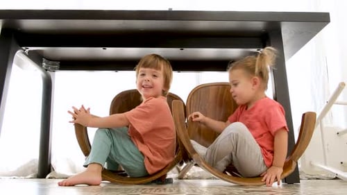 Happy Siblings Playing Under Table