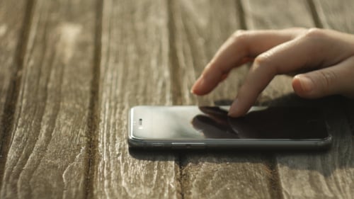 Hand Interacting With a Smartphone on Wood