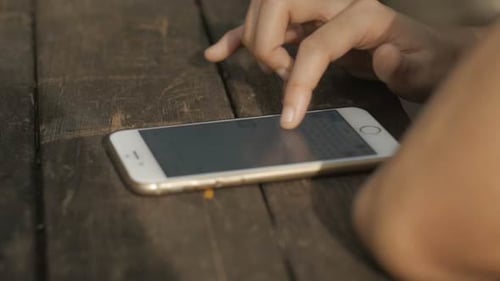 Fingers Interacting with Smartphone on Wood Table