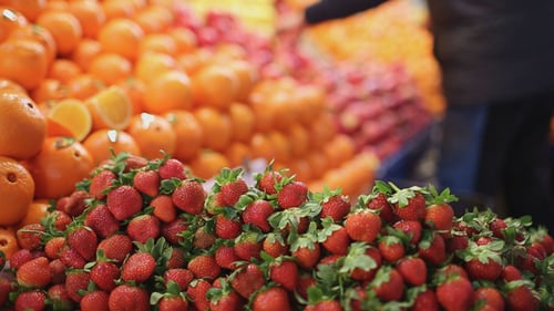 Fresh Strawberries and Oranges at a Market Stand