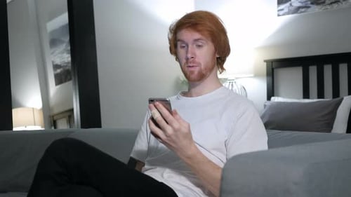 Redhead Man Video Chats at Home on Smartphone