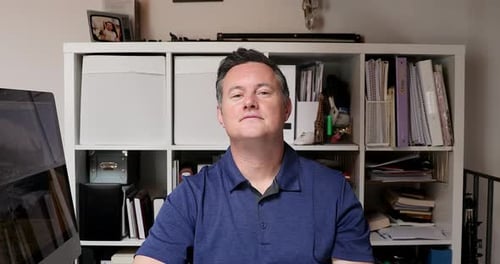 Man Smiling and Talking in Front of Bookshelf