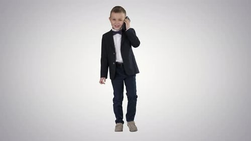 Smiling Boy in Suit Walks While Talking on Phone