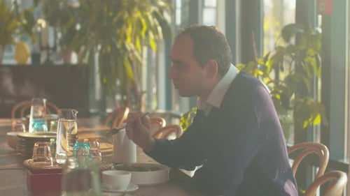Man Sit at a Table in Cafe and Eat Salad
