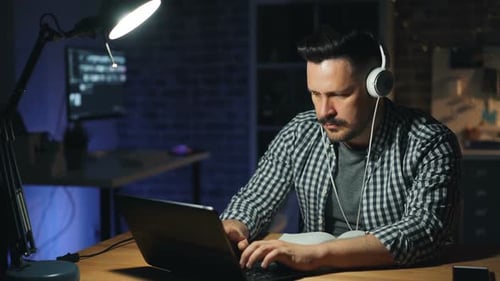 Tired Office Worker Turning Off Lamp and Laptop and Leaving Workplace at Night