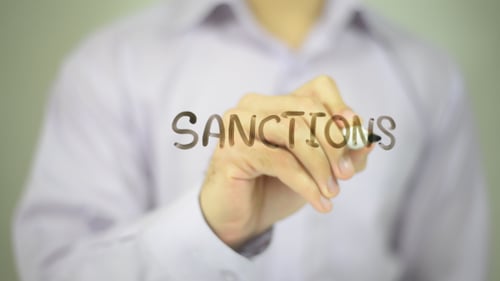 Hand Writes Sanctions on Glass