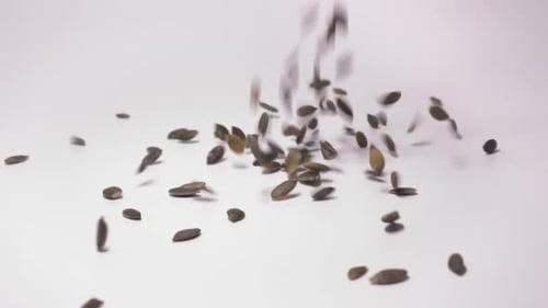 Pumpkin Seeds Falling onto White Surface