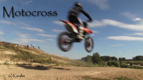 Motorcycle Racing Across a Dirt Track on Sunny Day
