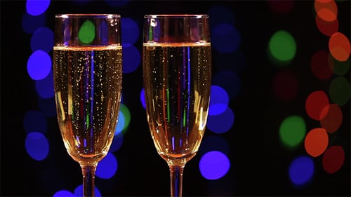 Two Champagne Glasses with Celebration Lights Behind