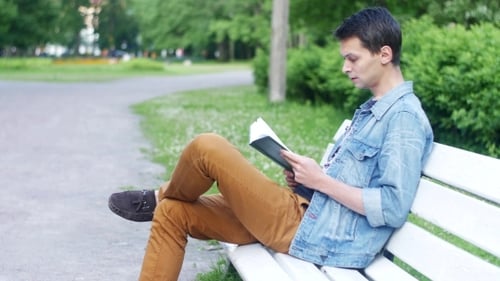 Junge sitzen auf einer weißen Bank und lesen das Buch