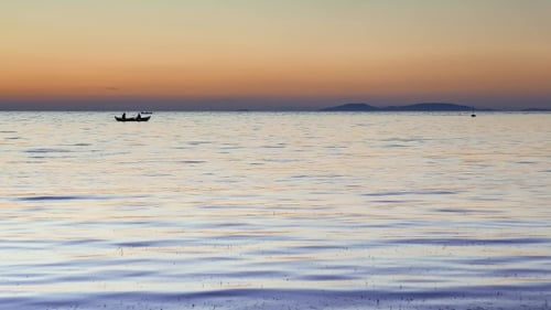 People in Boat on Calm Ocean at Sunset