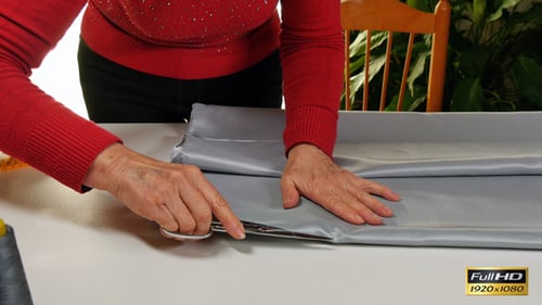 Adult Cutting Gray Fabric with Scissors at Table
