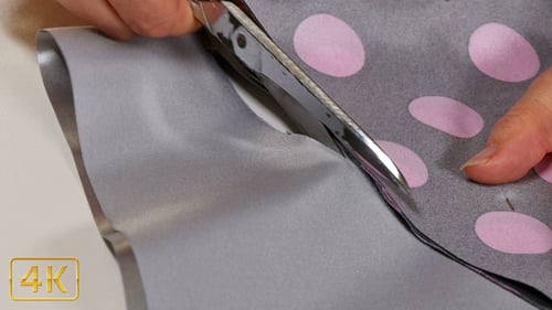 Adult Cutting Grey Polka Dot Fabric With Scissors