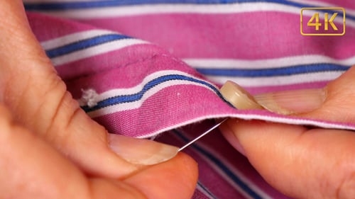 Close Up of Hands Sewing Button on Shirt