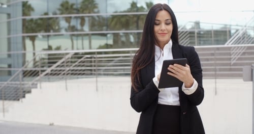 Businesswoman Uses Tablet Outdoors by Modern Office Building