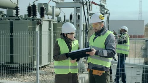 Engineers Inspecting Power Station with Power Transformers