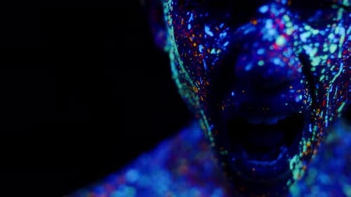 Closeup Man Face in Dark Studio Painted Fluorescent Paints and Scream Front View