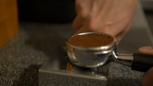 Tamping Fresh Coffee Grounds in Portafilter Close Up
