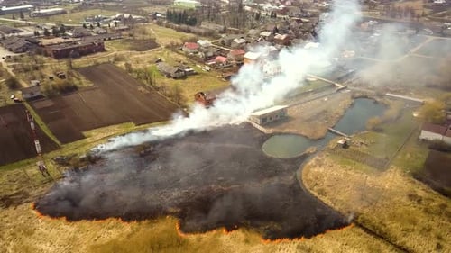Aerial View of a Field with Dry Grass Set on Fire with Orange Flames and High Column of Smoke