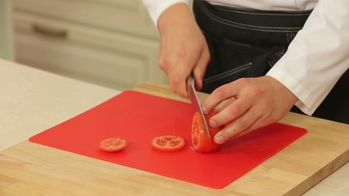 Chef Slicing a Tomato on Cutting Board