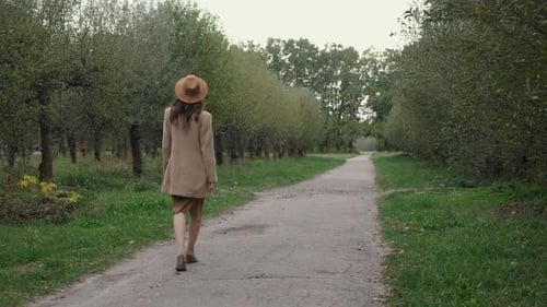 Woman Strolling in a Green Park on a Path