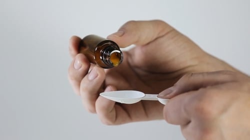Les mains de l'homme versent le médicament dans la cuillère