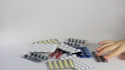 Hand Holding Pill Blister Pack on White Surface