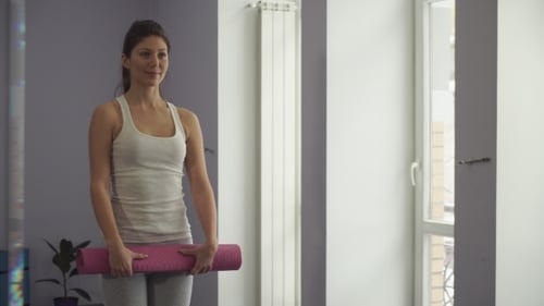 Woman Unrolls Yoga Mat to Exercise Indoors