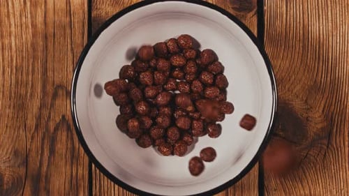 Chocolate Cereal Falling Into a White Bowl