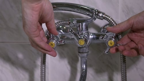Der Mann öffnet das Leitungswasser im Badezimmer